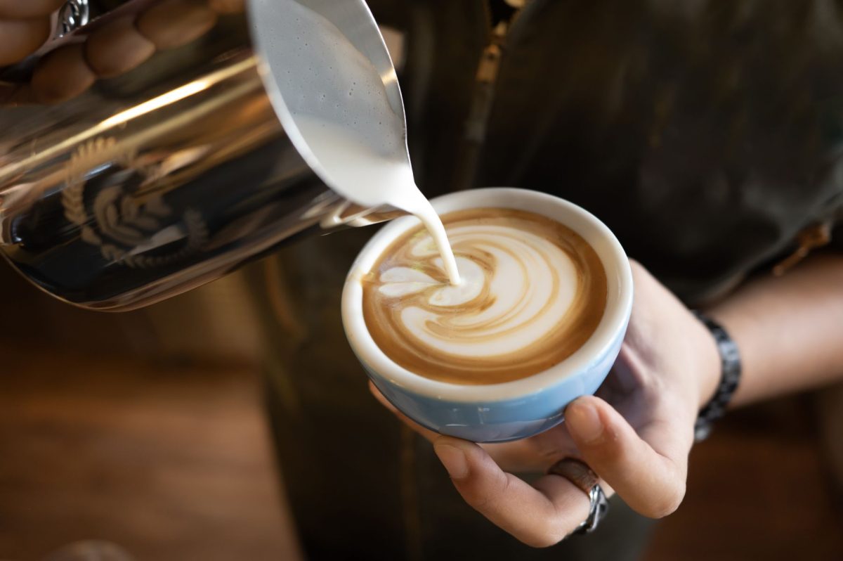barista pouring milk into a latte